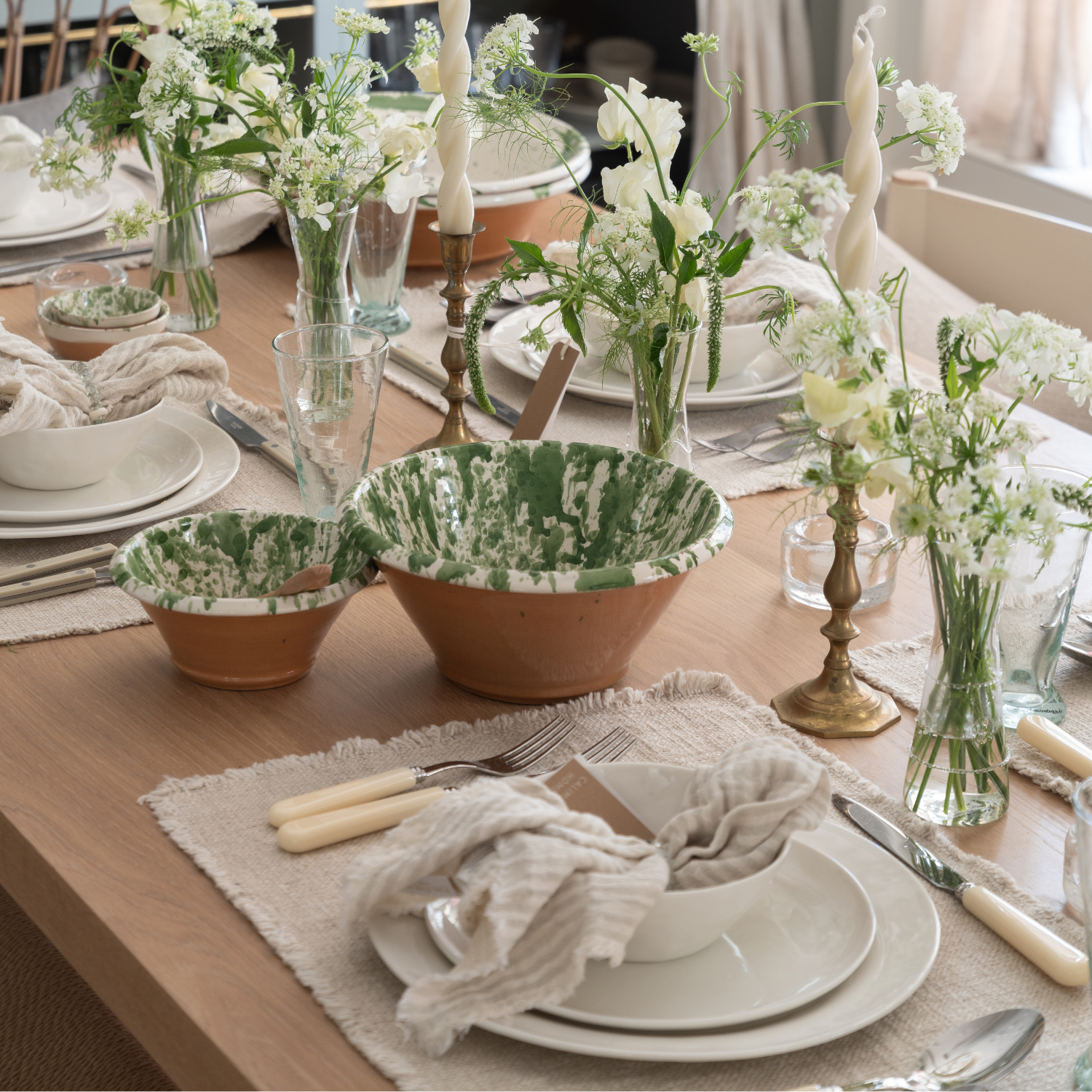 Elegant table setting with floral arrangements, bowls, and cutlery on a wooden table.