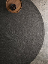 Armadillo Braid Rug in Charcoal, a second view of the hand-braided wool blend rug in a styled interior