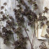 Artificial Hogweed by Abigail Ahern laid flat on a gray surface with scissors and paper