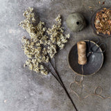 Artificial Sedge Winter Dew by Abigail Ahern laid flat on a gray surface beside twine