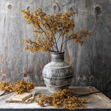 Artificial Sedge Winter Saffron stems by Abigail Ahern in a rustic vase on a wooden console