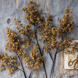 Artificial Sedge Winter Saffron by Abigail Ahern laid flat on a weathered wood surface