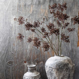 Artificial Woodland Yarrow stems by Abigail Ahern arranged in a weathered stone vase against a timber wall