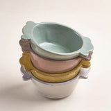 Il Buco Assisi ceramic bowls in a stacked arrangement featuring dove grey, yellow, and sage green hand-glazed finishes.