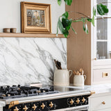 Sir Madam Bakers Dozen beechwood spoons in ceramic crocks on a marble kitchen counter near a gas stove