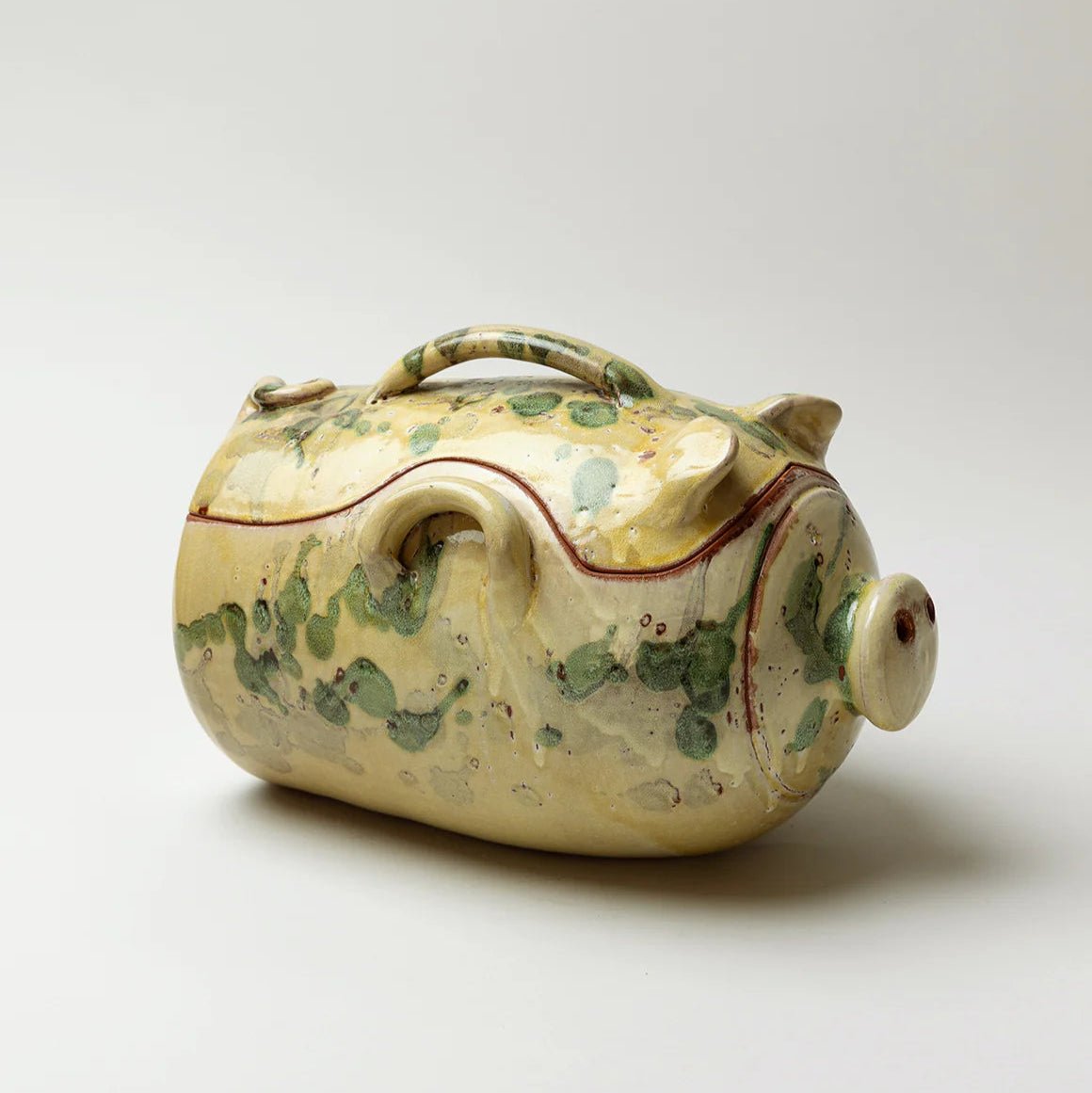 Decorative ceramic piggy bank with green and brown patterns on a white background