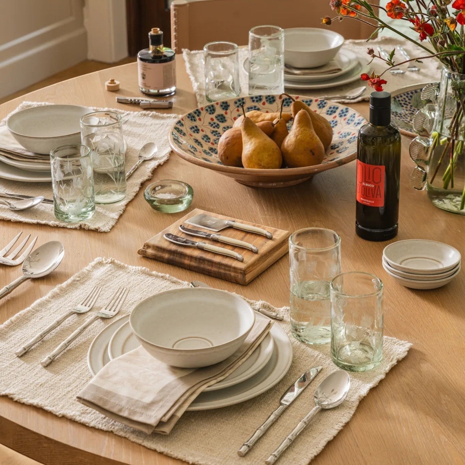 Calimia Home Biancolilla Extra Virgin Olive Oil bottle on a beautifully set wooden dining table with place settings