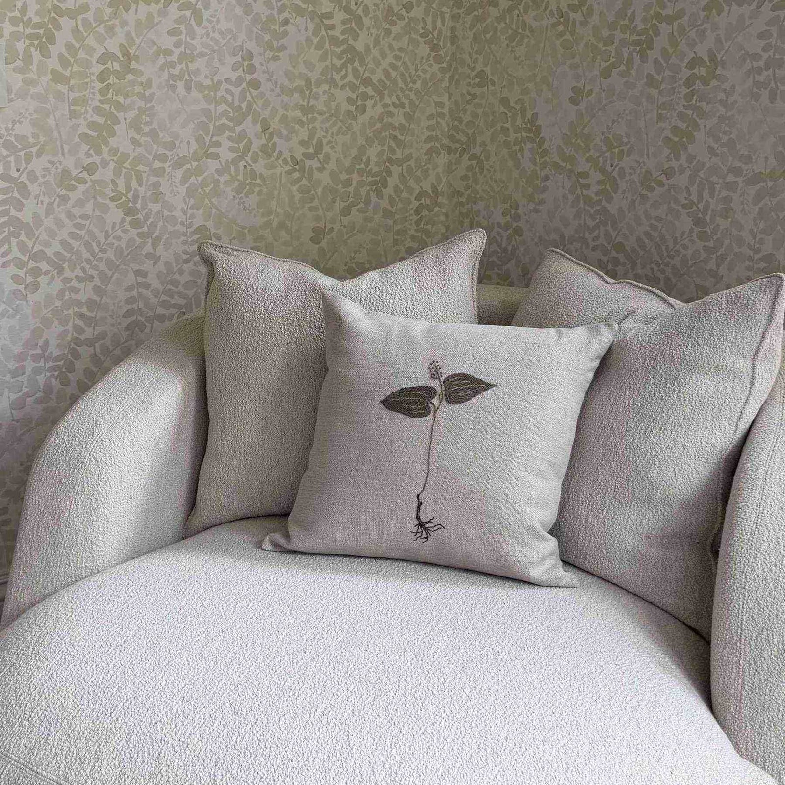 Botanical Embroidered Pillow by One Bi One — hand-embroidered plant motif on linen, styled on a boucle chair