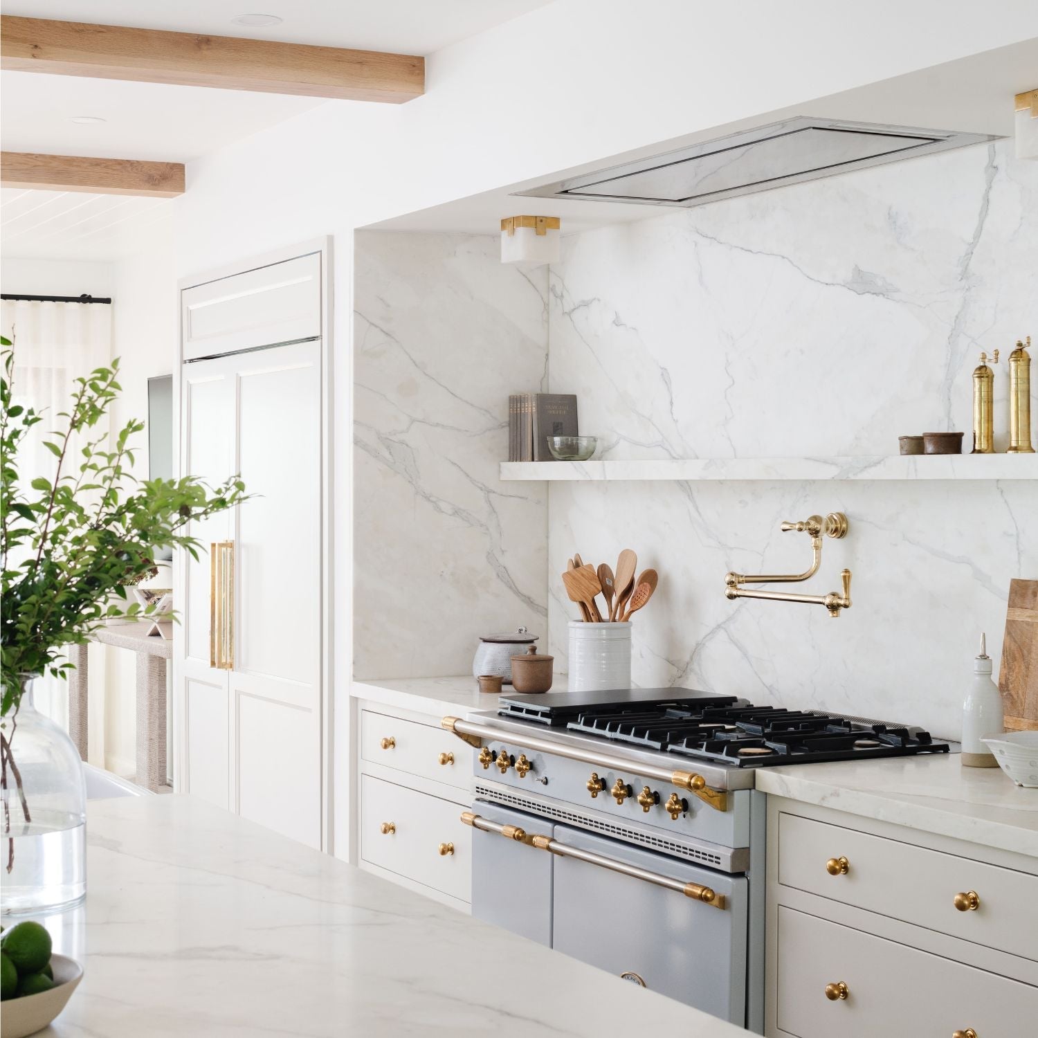 White marble kitchen with brass hardware and French range styled by Calimia Home