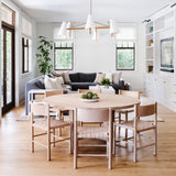 Open dining area with round white oak table, woven chairs, and bright white built-ins