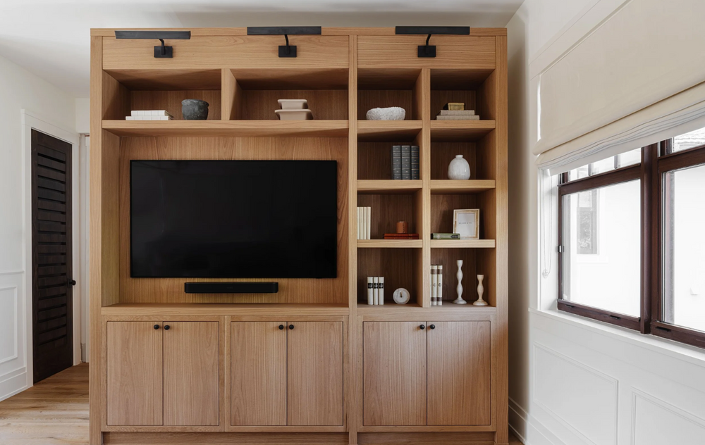 White oak media built-in with open shelving and styled ceramics in the family room