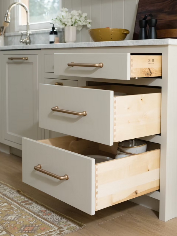 Open dovetailed drawer boxes with brass pulls in Townhouse Line custom cabinetry