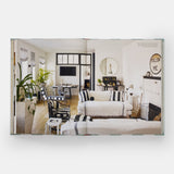 Calimia Home Everybody Loves Stripes book open to a spread showing a bright living room with black and white striped upholstery.