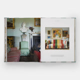 Calimia Home Everybody Loves Stripes book open to a spread showing a green drawing room with striped armchairs and a bust.