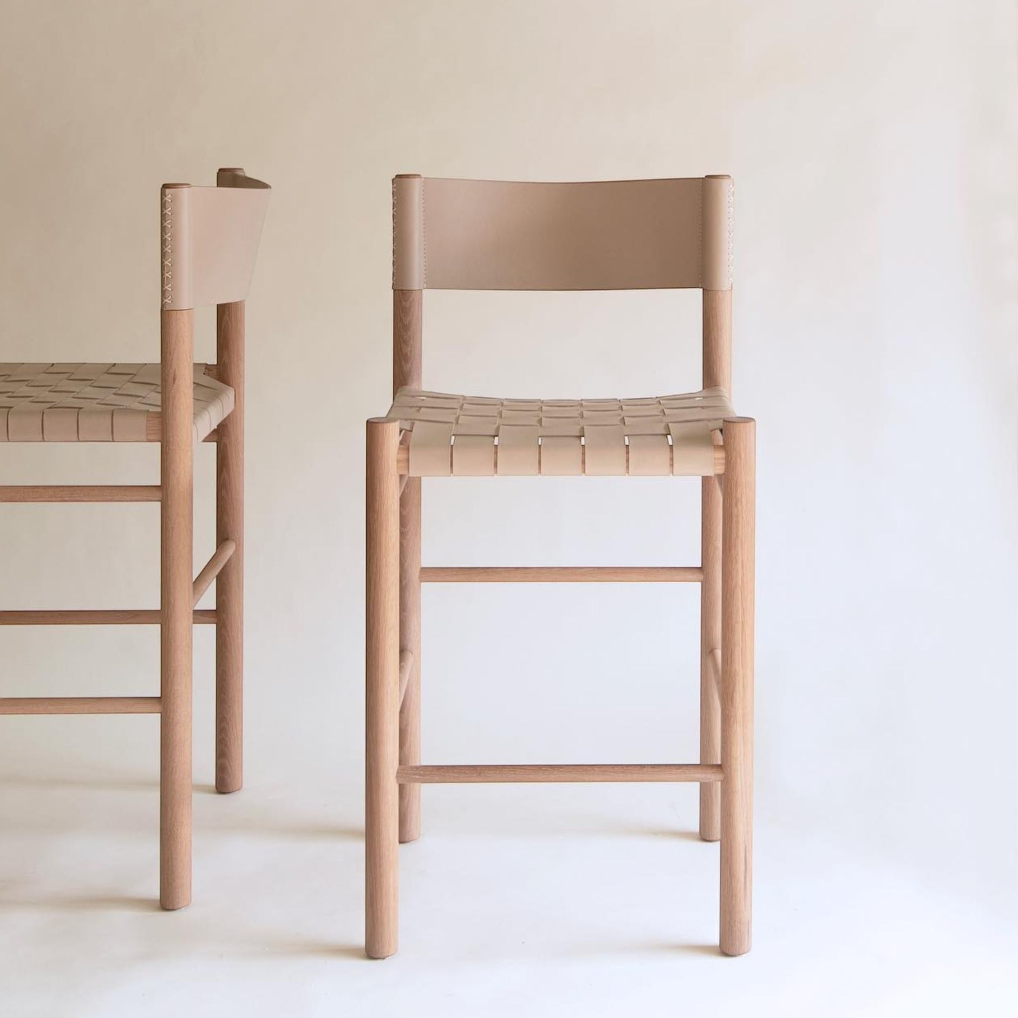 Calimia Home Flag counter stool featuring a solid oak frame and woven natural leather seat with a supportive backrest.