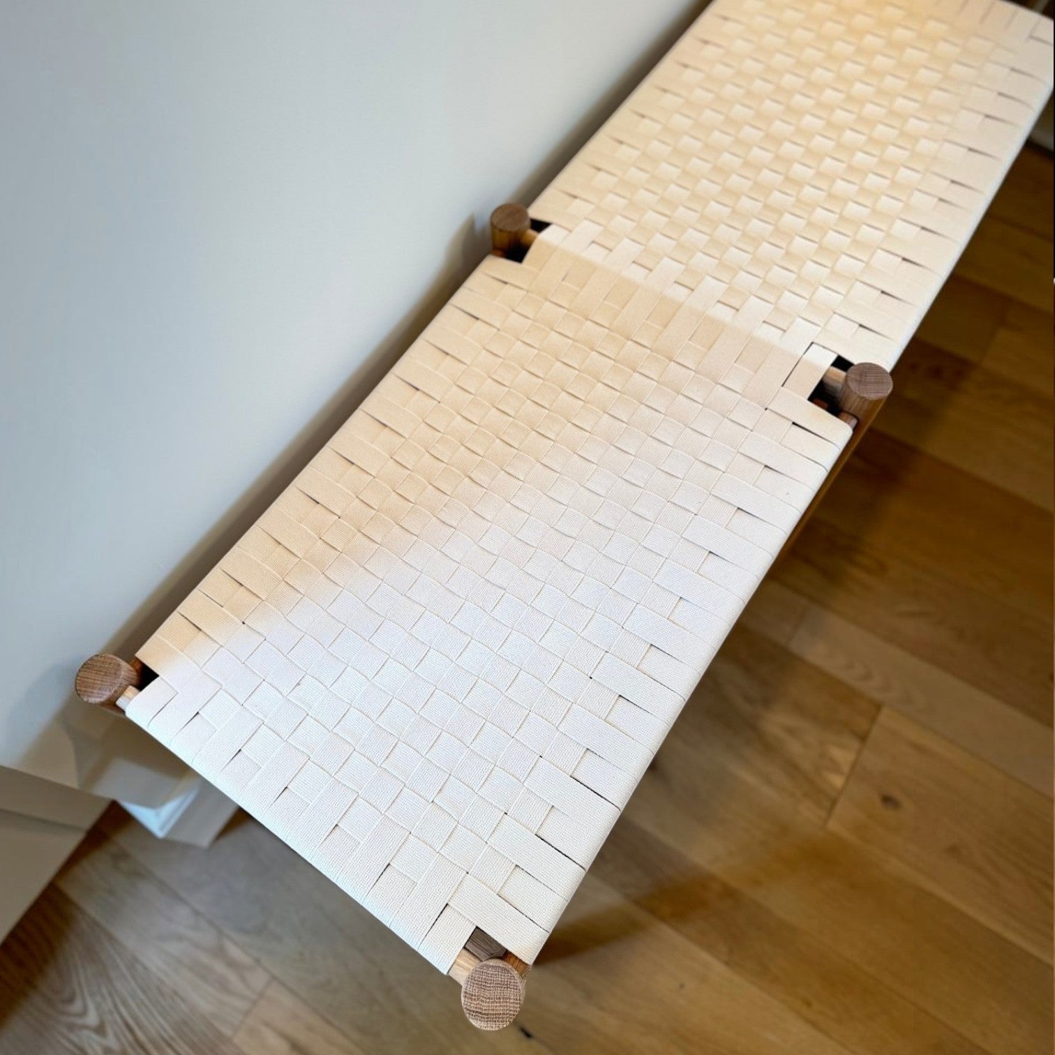 Calimia Home Gaon bench featuring a solid white oak frame and a handwoven white canvas ribbon seat in a top-down view.