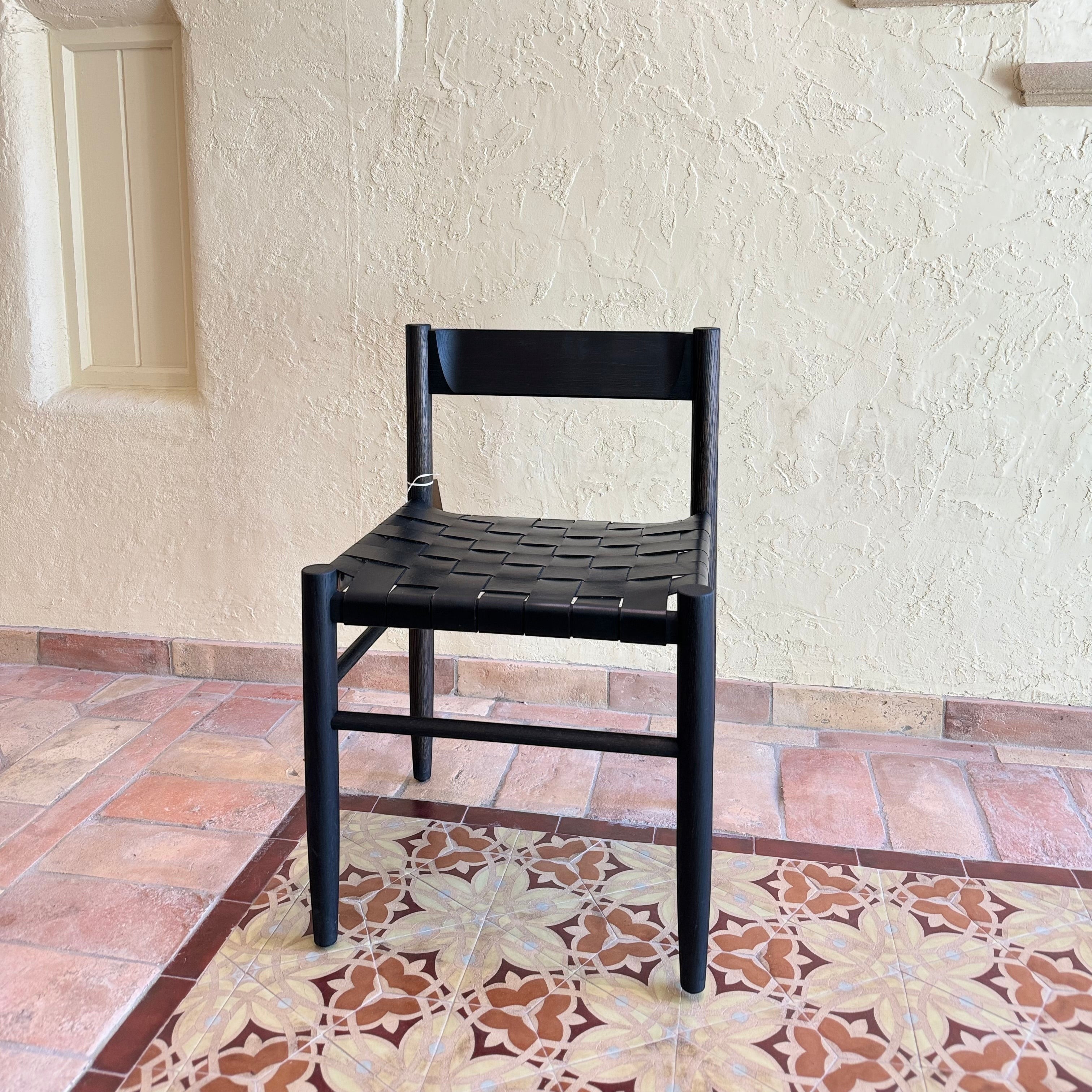 Calimia Home Gaon chair featuring a black oak frame and a woven black leather seat in a modern sculptural design.