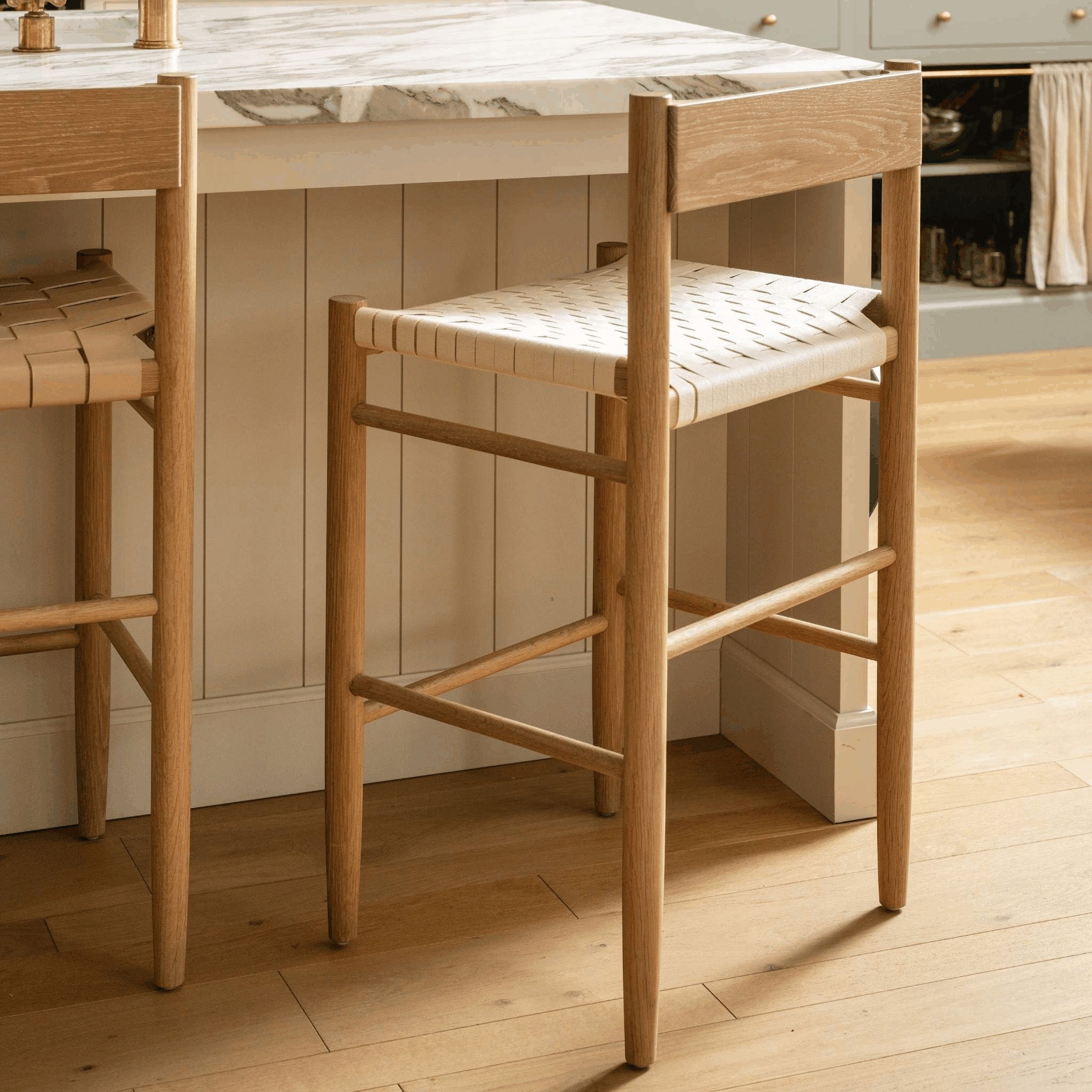 Calimia Home Gaon counter stool featuring a solid white oak frame and a woven natural leather seat in a kitchen.
