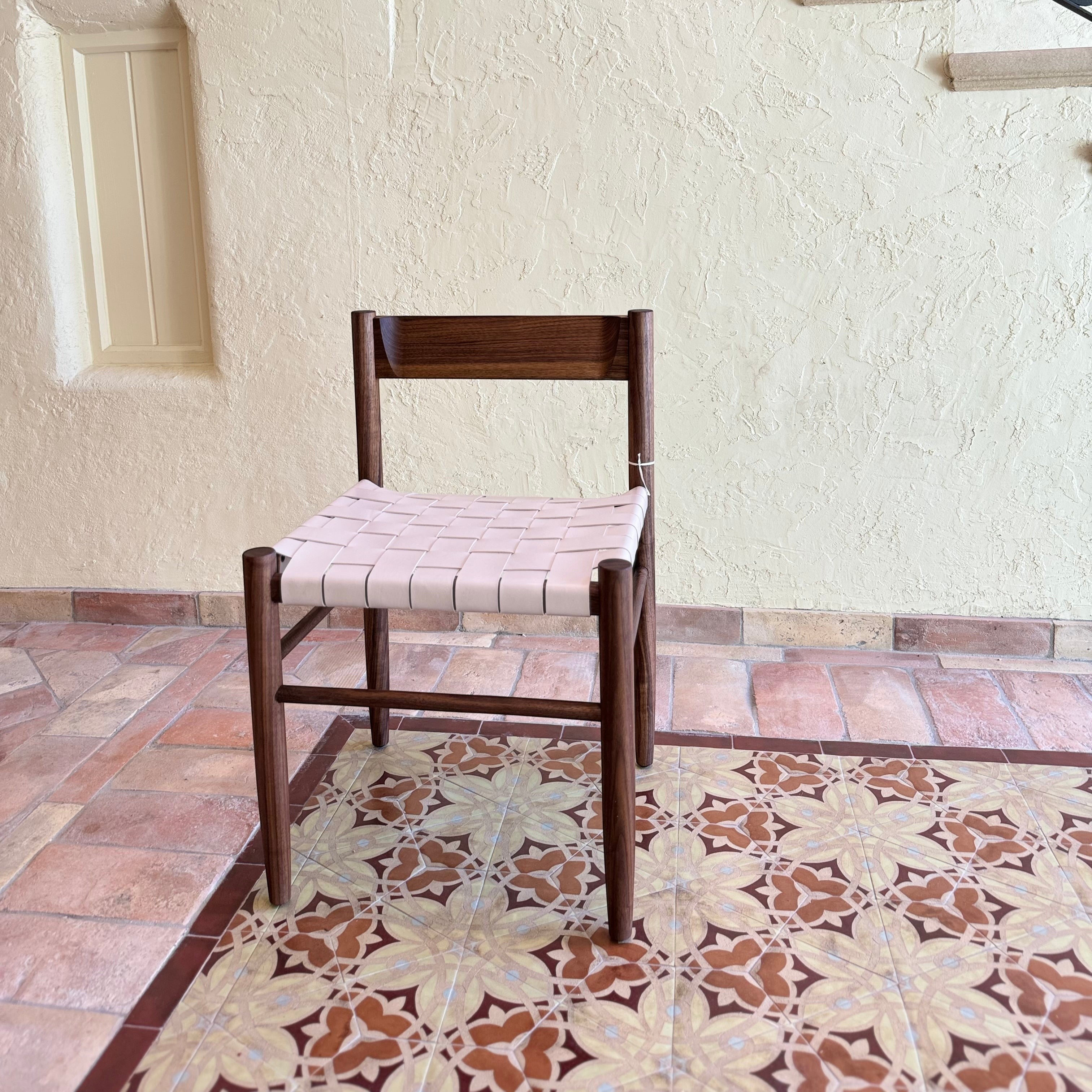 Calimia Home Gaon chair featuring a dark walnut wood frame and a woven cream leather seat in a modern sculptural design