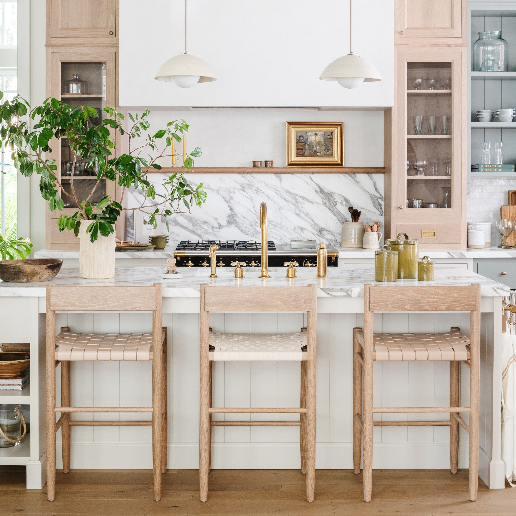 Calimia Home Gaon counter stools with white oak frames and woven natural leather seats in a bright modern kitchen.