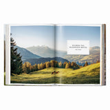 Calimia Home Great Escapes Alps book open to the Guarda Val Maiensäss Hotel spread with autumn larches and mountain views.