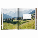 Calimia Home Great Escapes Alps book open to the Rote Wand spread showing a mountain village beneath alpine peaks.