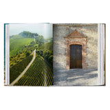 Calimia Home Great Escapes Italy book showing a vineyard landscape and a rustic stone building entrance