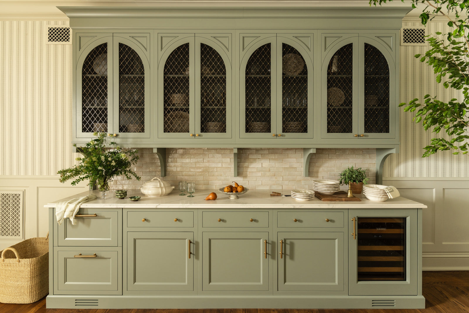 Butler's pantry with sage green cabinetry, arched mesh cabinet doors, and an integrated wine fridge