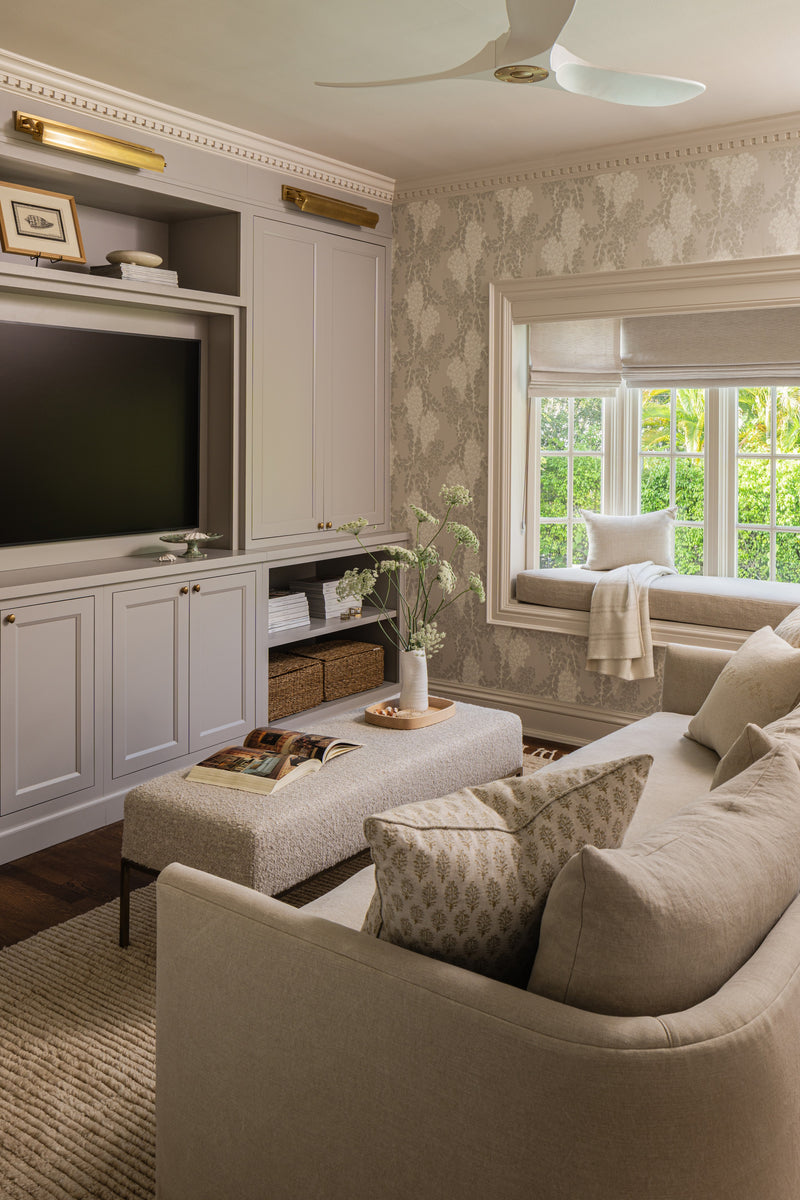 Den with wisteria wallpaper, a cushioned window seat, and a linen sofa