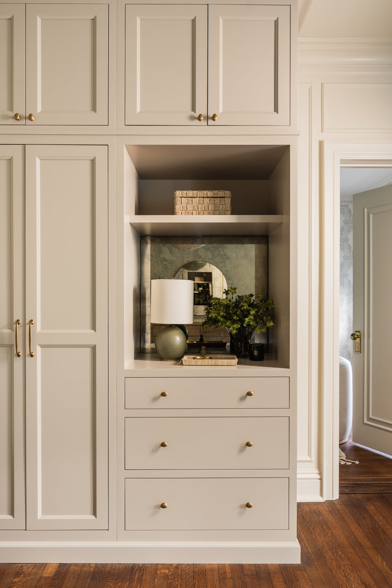 Hallway built-ins with an antique mirror niche, cream cabinetry, and brass hardware