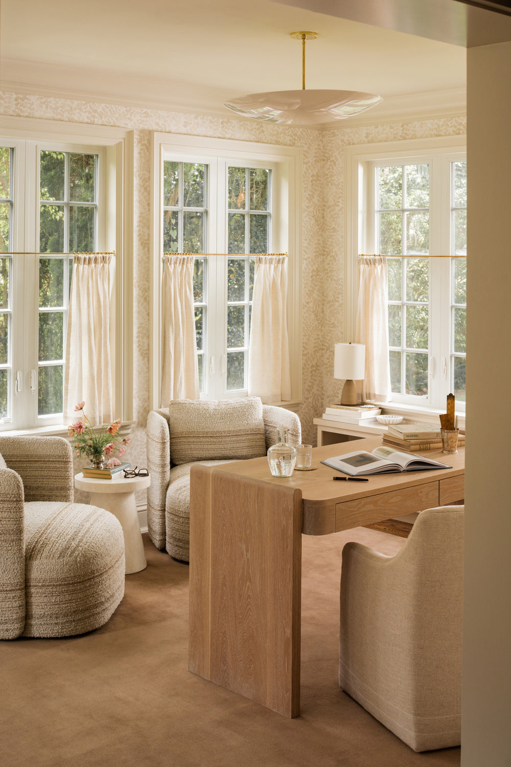Home office with an oak desk, bouclé swivel chairs, and a curtained bay window seat