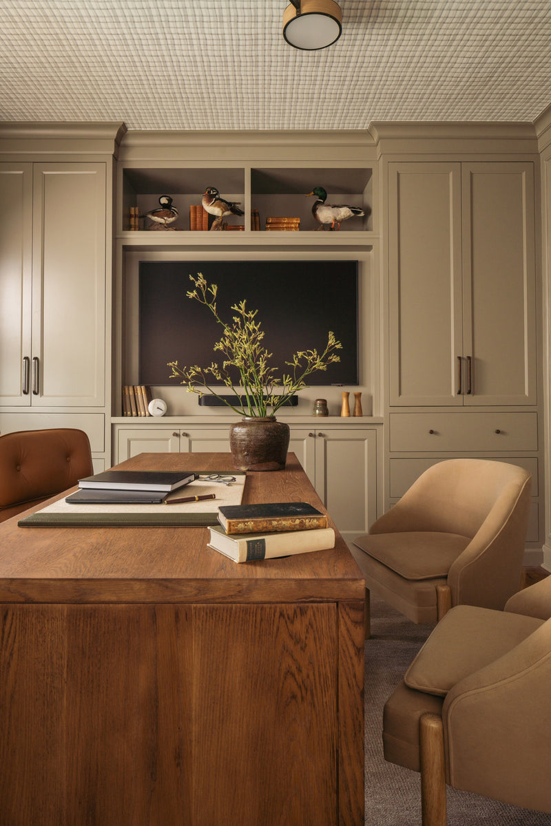Home office with built-in cabinetry, a concealed television, and antique duck decoys on open shelves