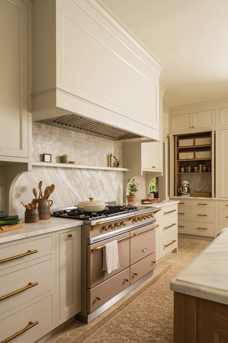 Kitchen with a Lacanche range, marble slab backsplash, and a plaster hood in cream cabinetry