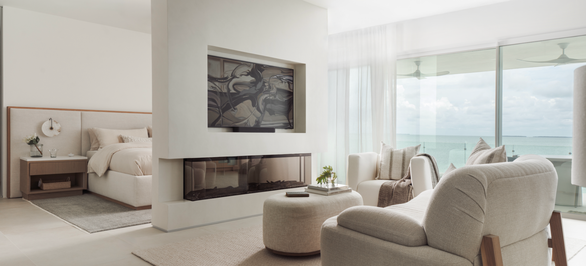 Oceanfront primary suite with linear fireplace and neutral seating, full-service design by Calimia Home in Miami