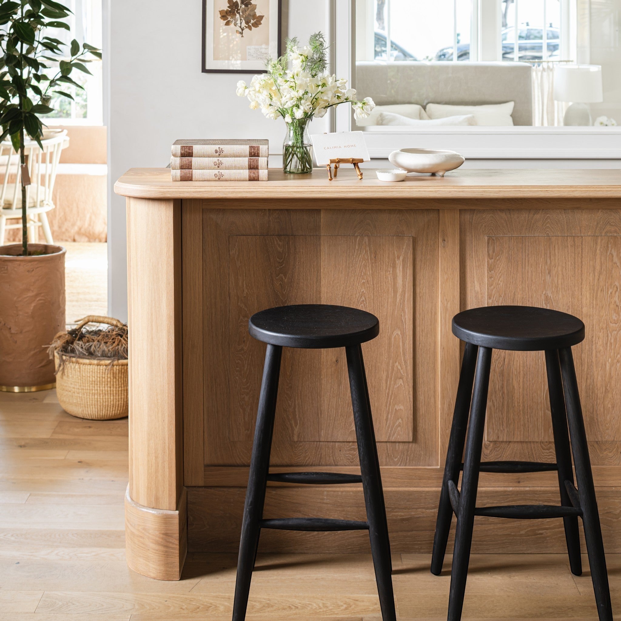 Calimia Home Omah Stool set in black stained wood with round seats and tapered legs at a kitchen breakfast bar