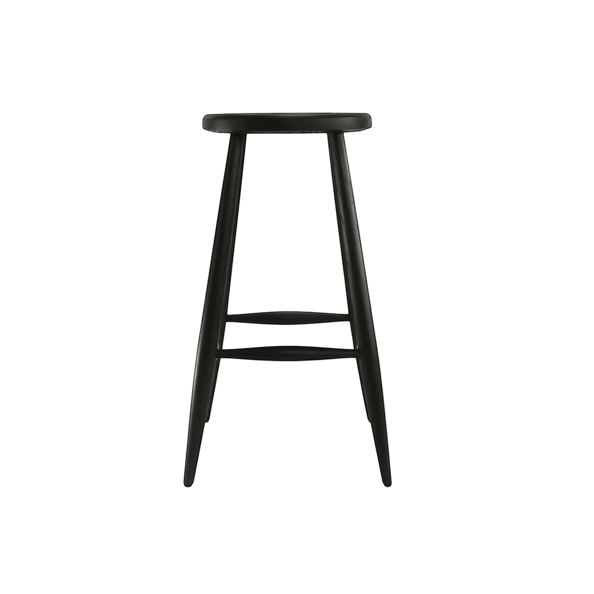 Calimia Home Omah stool in black stained wood with a round seat, tapered legs, and integrated footrests.