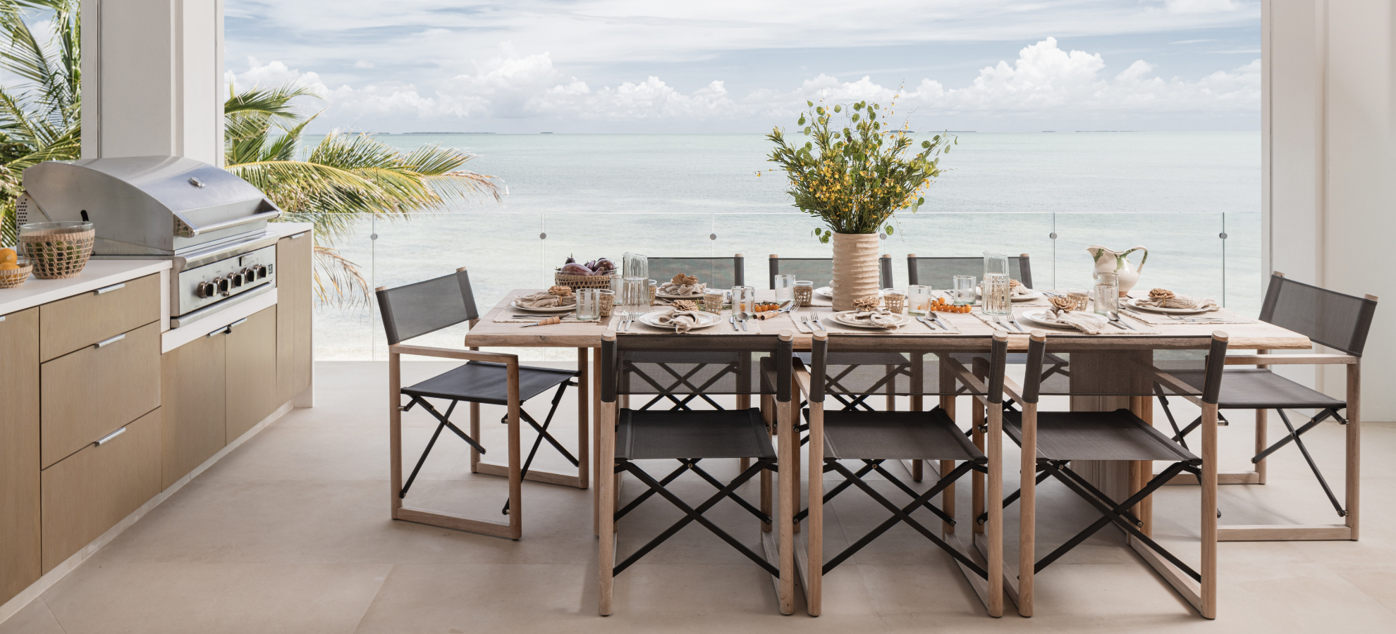 Oceanfront outdoor dining table with director chairs and built-in grill at the Peaceful Waters home, Islamorada