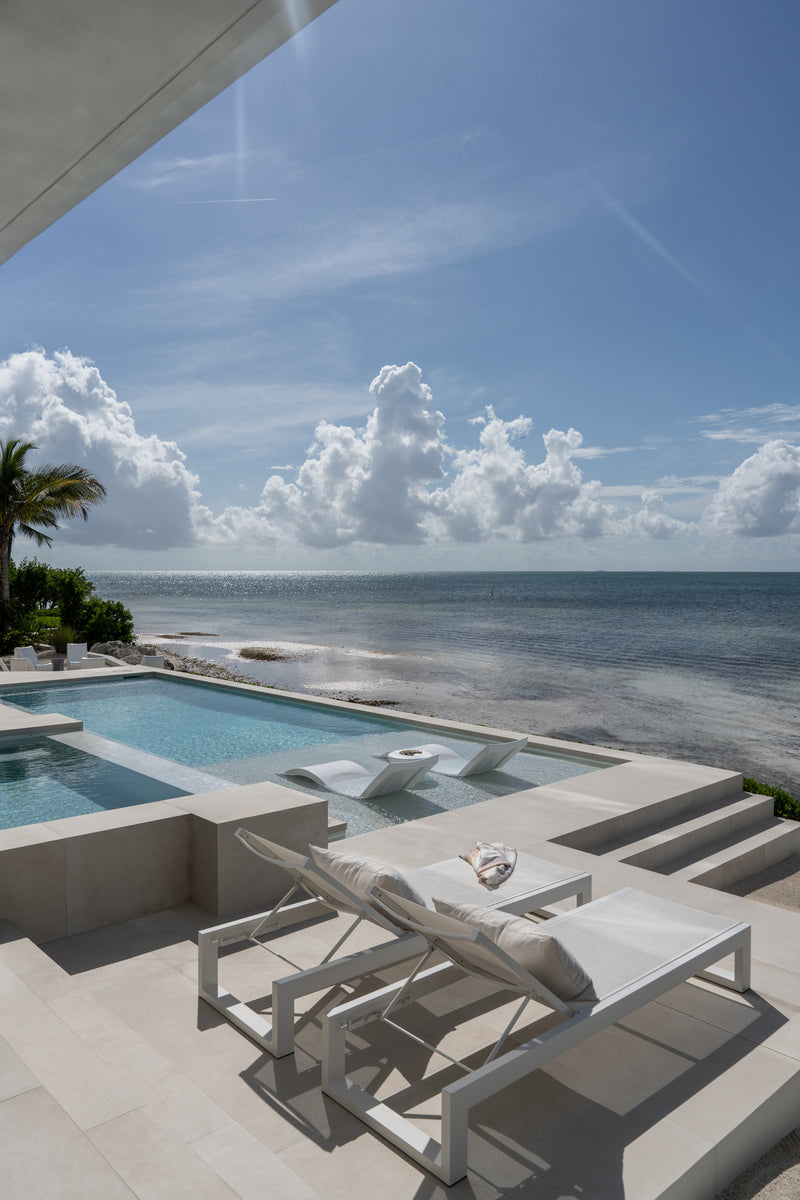 Infinity-edge pool with white loungers overlooking the Atlantic at the Peaceful Waters home, Islamorada