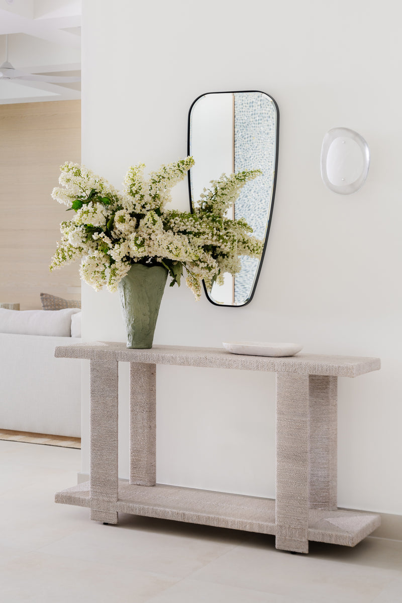 Textured limestone console styled with an organic-form mirror and white flowering branches
