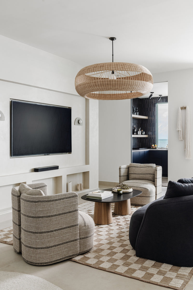 Media lounge with rattan chandelier, striped swivel chairs, and checkerboard rug in the Peaceful Waters home