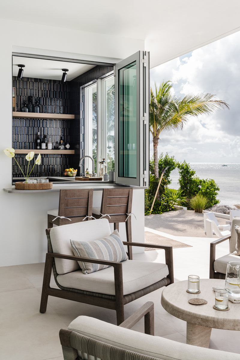 Outdoor bar with pass-through window and teak lounge seating by the sea at Peaceful Waters, Islamorada