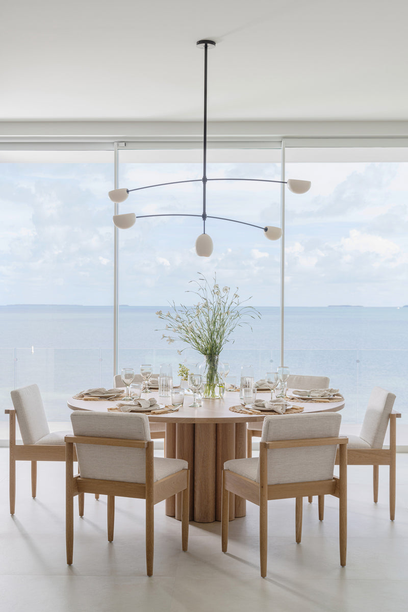 Round pedestal dining table set with glassware and linen chairs overlooking calm Florida Keys water