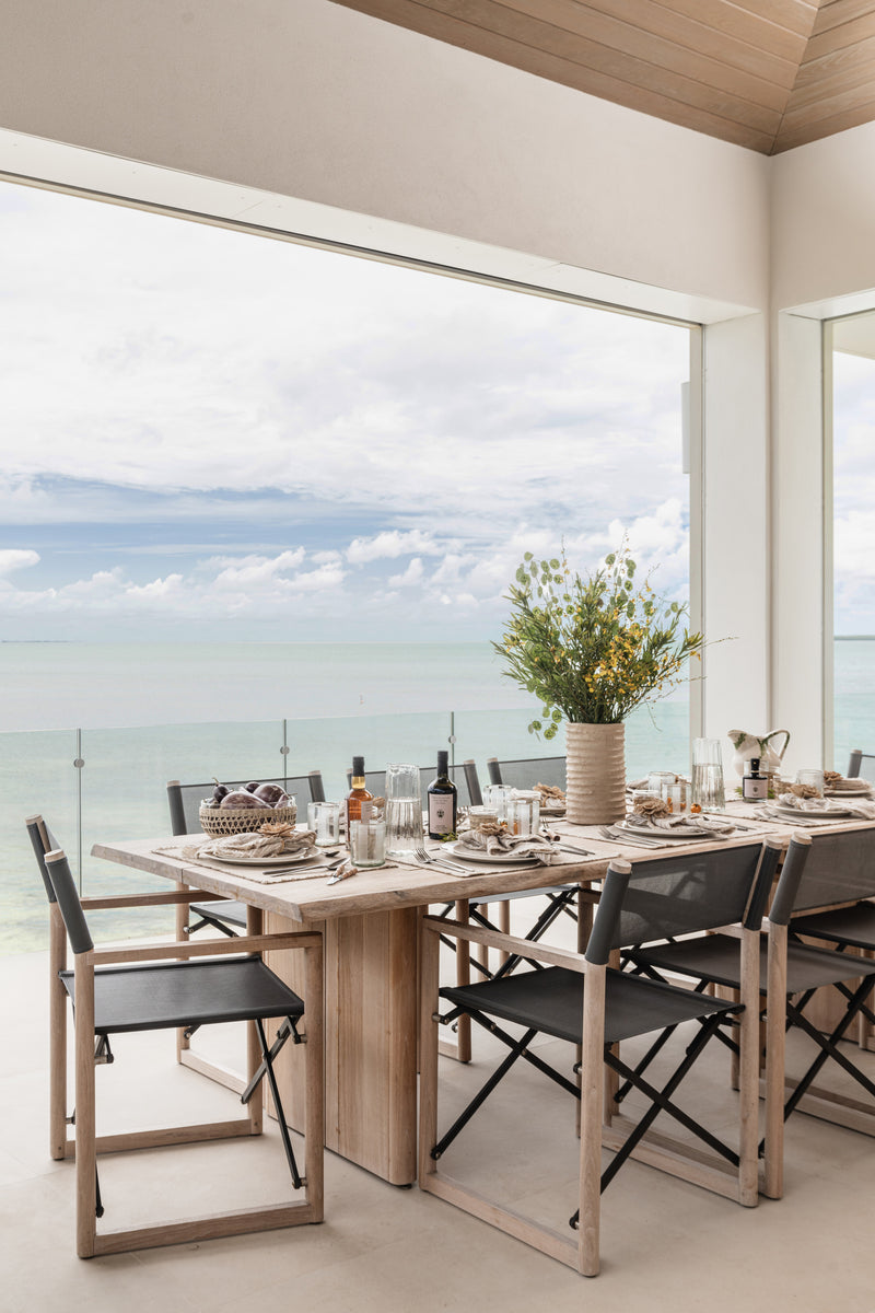 Covered terrace dining with wildflower centerpiece and black folding chairs above the sea at Peaceful Waters
