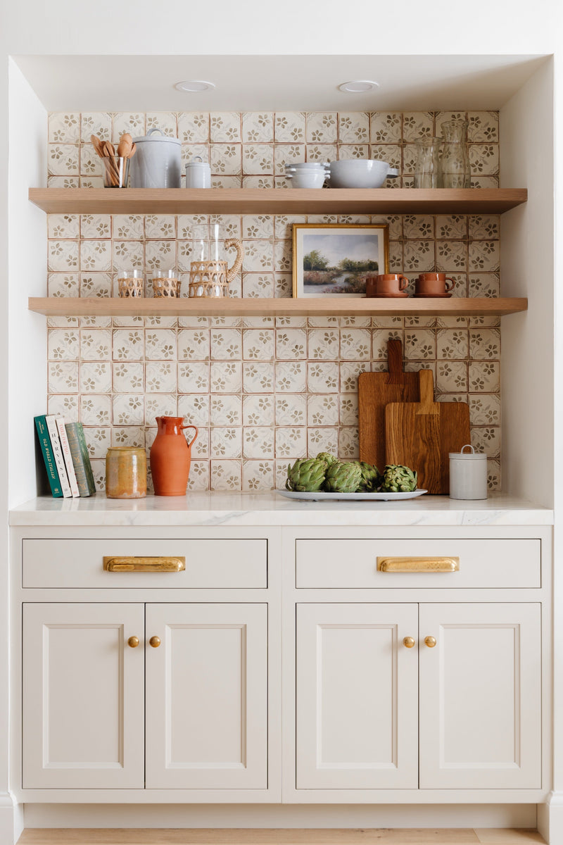Butler's pantry with patterned tile, floating oak shelves, and brass hardware styled with artichokes