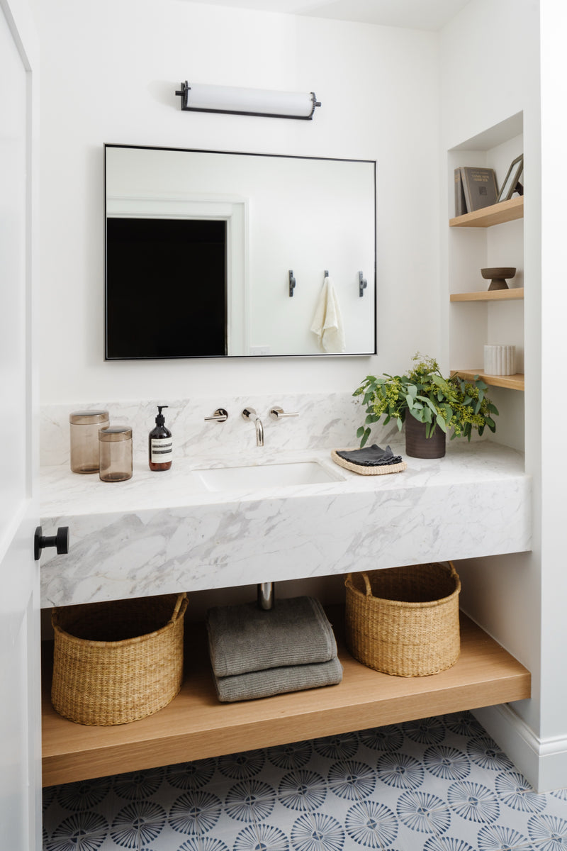 Floating marble vanity with wall-mount faucet, woven baskets, and oak shelving in the Raynolds Residence