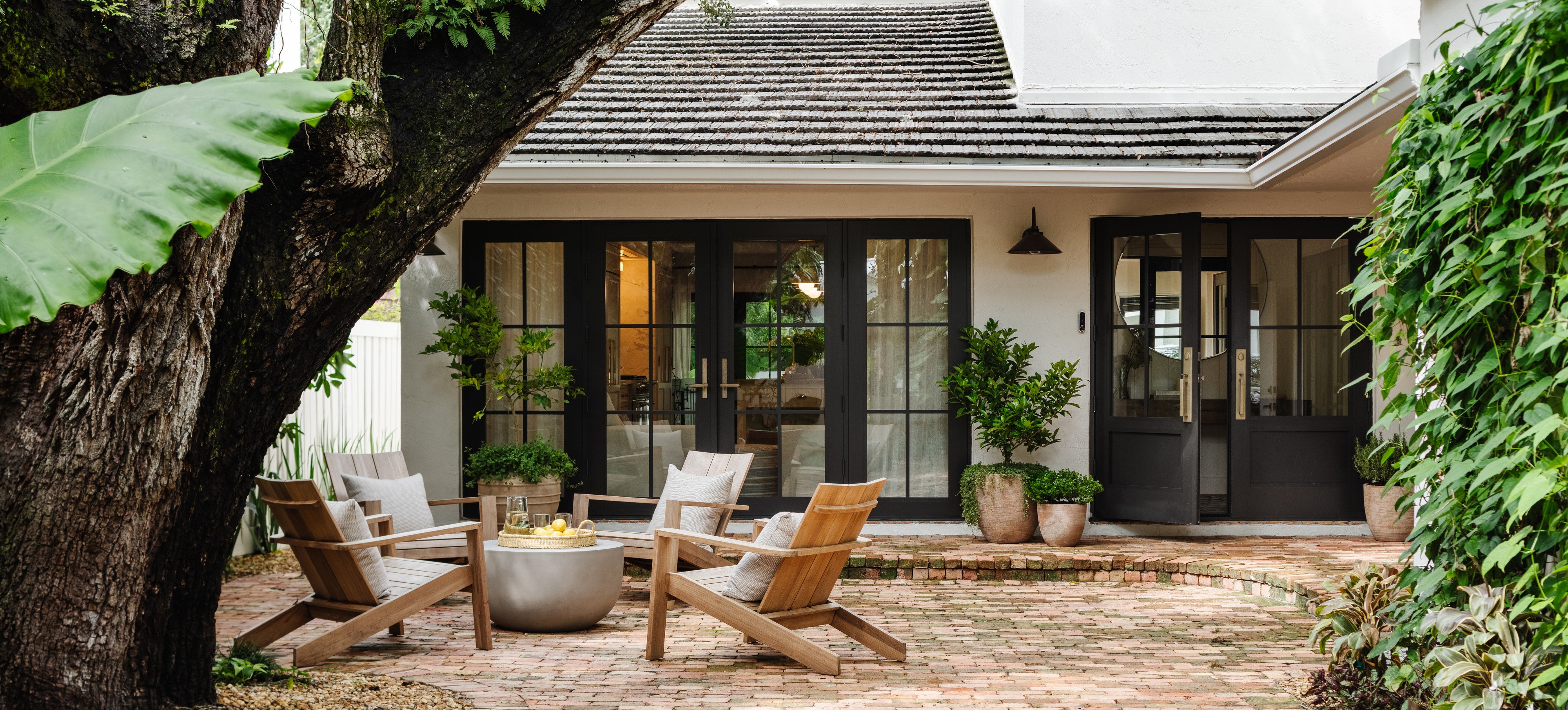 Renovated historic cottage with black steel doors and gravel courtyard seating in the Raynolds Residence, Coconut Grove