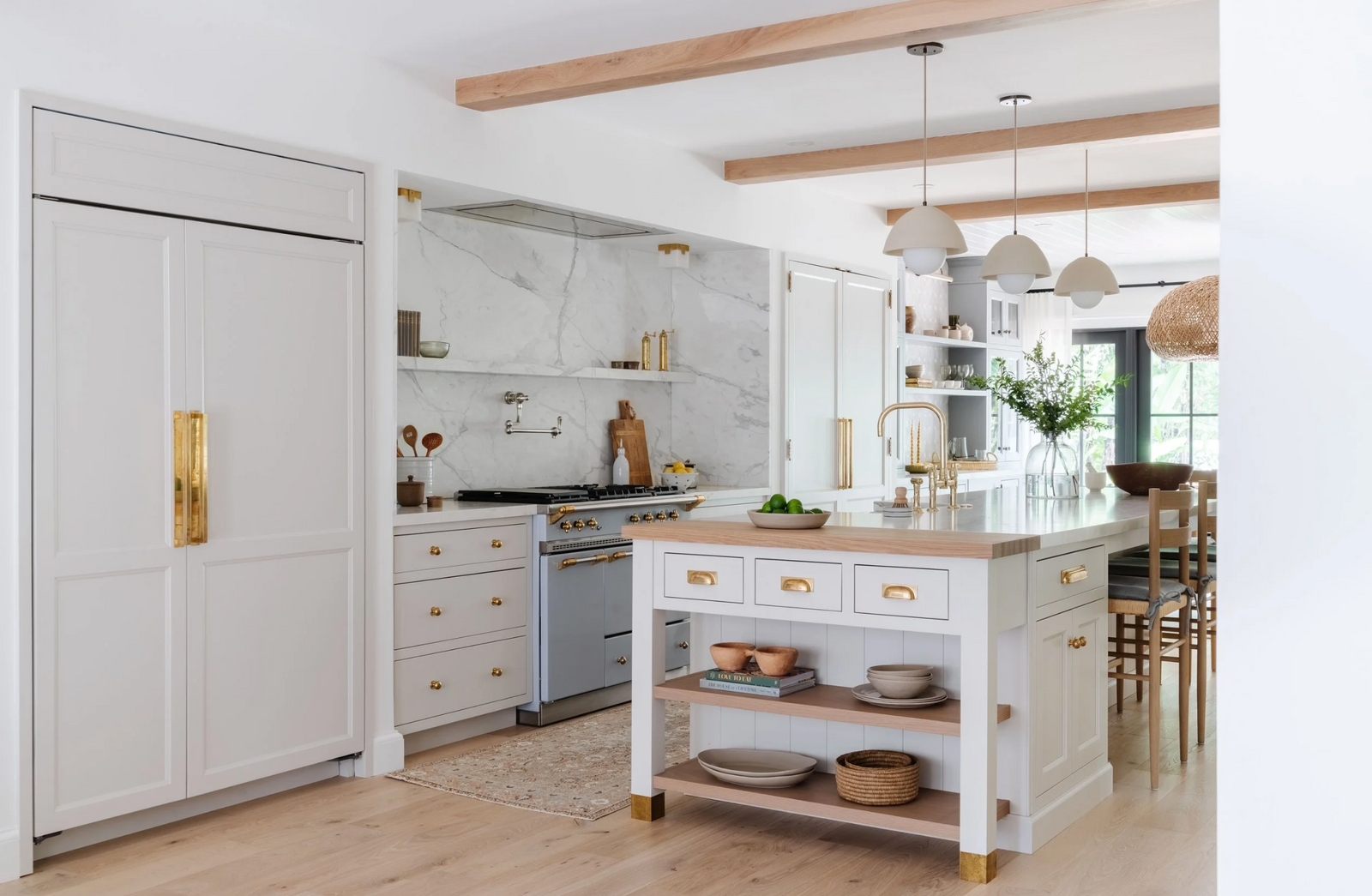 Light-filled kitchen with paneled refrigerator, oak ceiling beams, and freestanding marble-top island