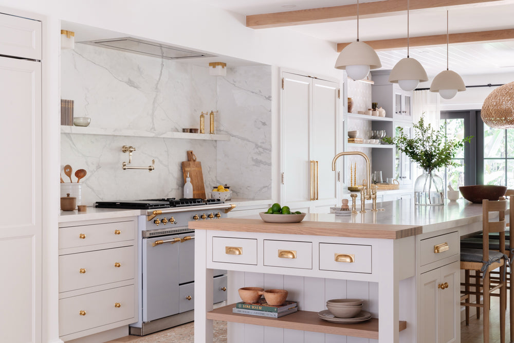 Cream kitchen with a Lacanche range, marble-topped island, and dome pendants in the Raynolds Residence, Coconut Grove