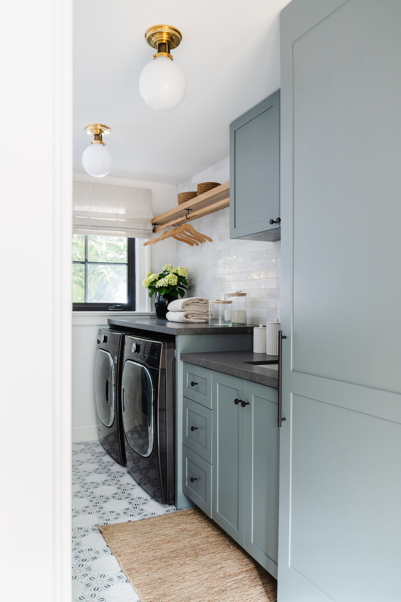 Blue-gray laundry room with patterned tile floor and brass globe lights in this Coconut Grove renovation
