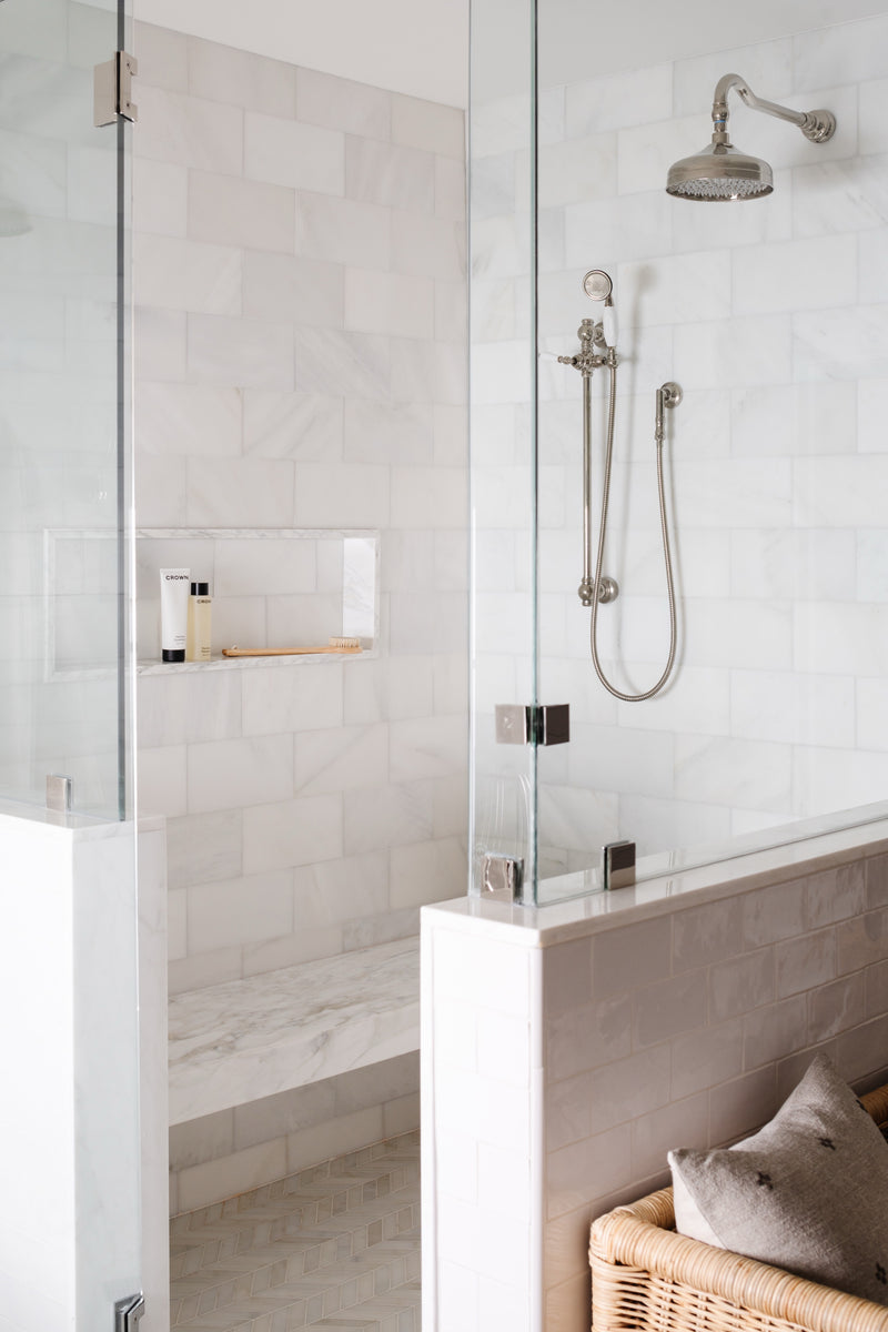Marble walk-in shower with glass partition, rain shower head, and built-in niche
